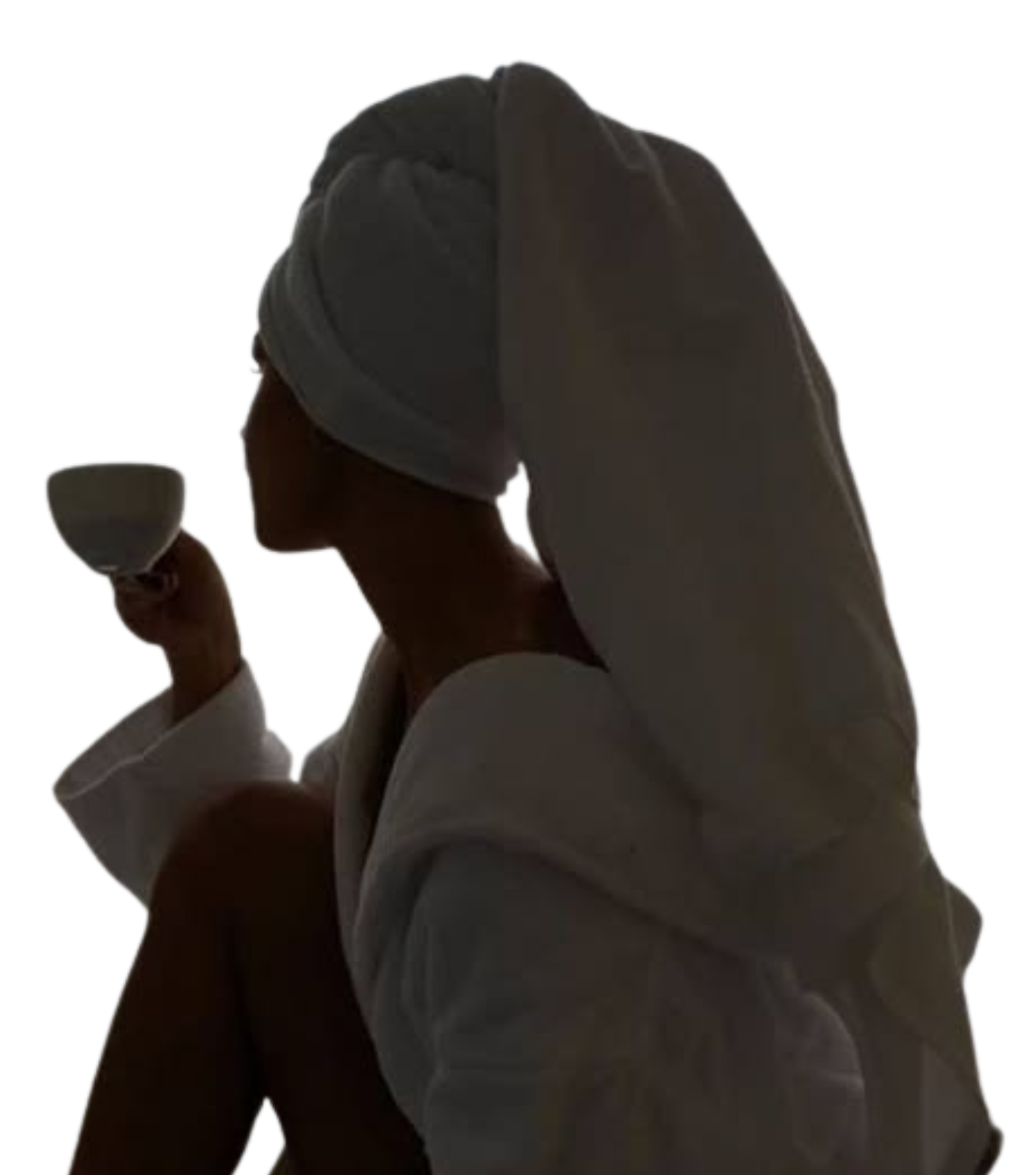 Femme en peignoir de 3/4 buvant un café et se détendant, serviette sur la tête.