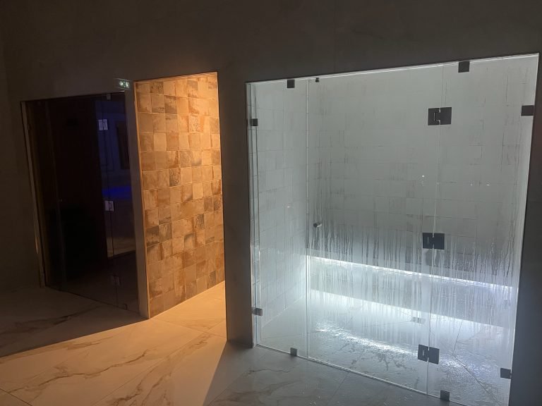 Salle évasion avec cabine de douche diffusant une lumière chaude et hammam avec éclairage froid et vapeur visible.