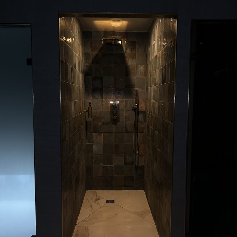 Cabine de douche ouverte avec une lumière chaude et tamisée.
